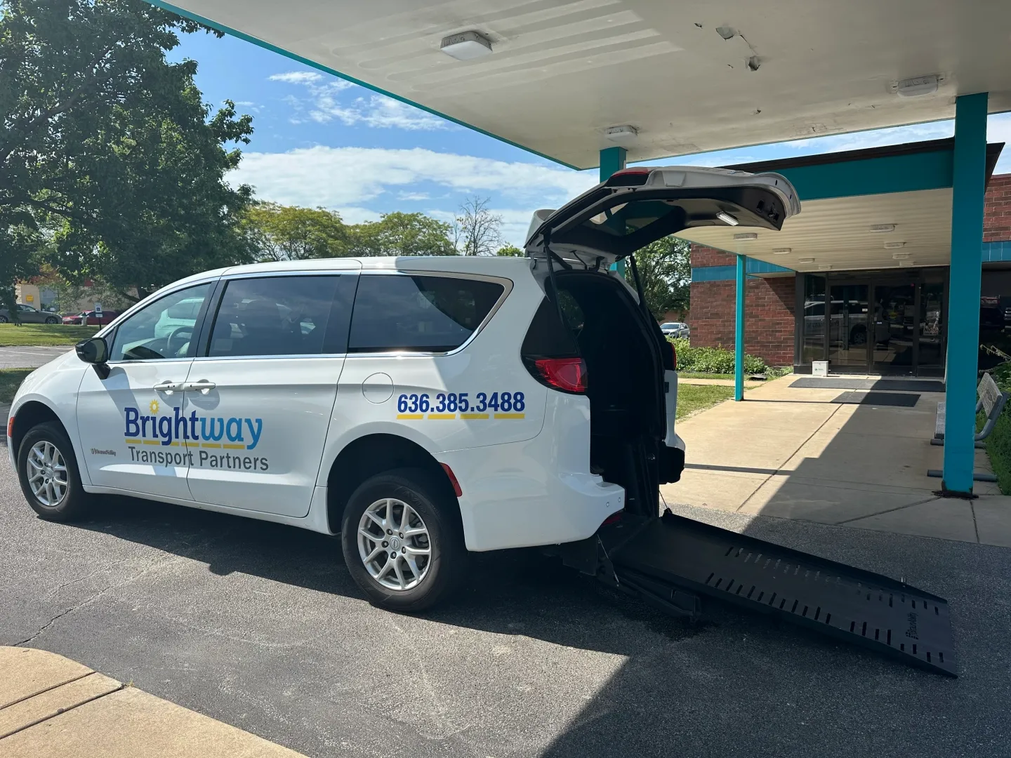 White van with wheelchair ramp extended.